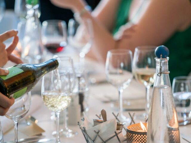 person pouring wine on clear wine glass