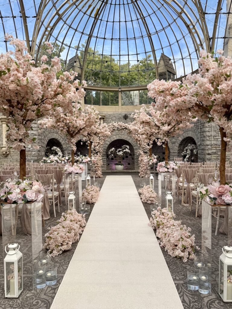 The aisle in the orangery with pink flowers at Tortworth Court in the Cotswolds and Gloucestershire.