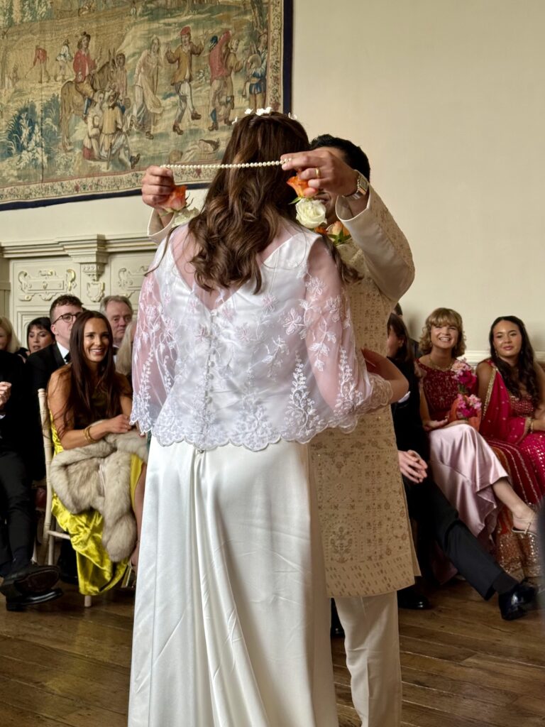 Groom placing necklace on bride during wedding ceremony at Elmore Court in Gloucestershire and the Cotswolds